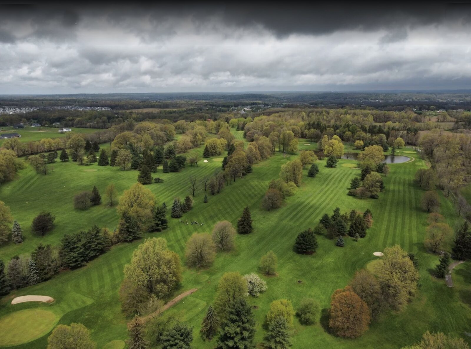Pine Valley Golf Course in Wadsworth from the air: fairways, mature trees, and a pond, with the town beyond