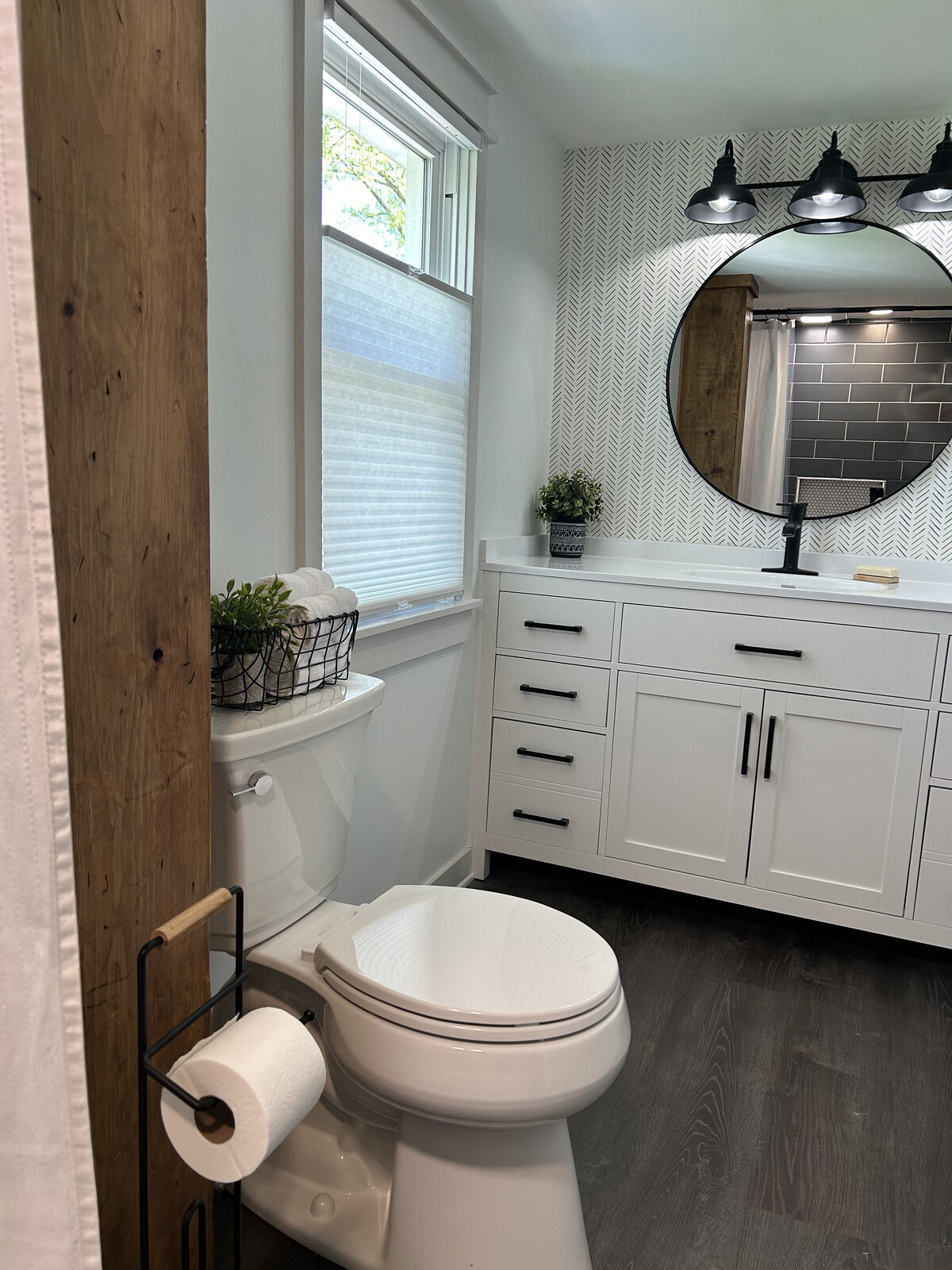 Upstairs full bath with white vanity, round mirror and black sconces