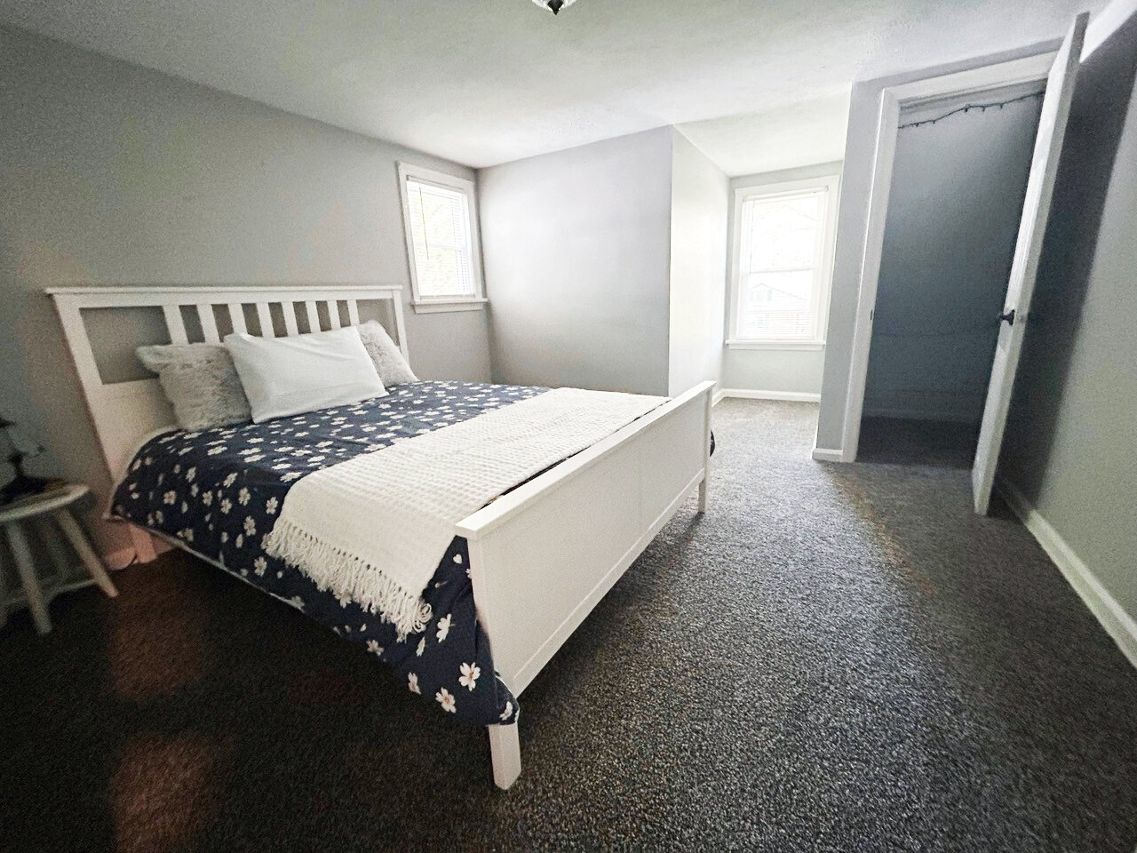 Bedroom with a white bed frame and two windows
