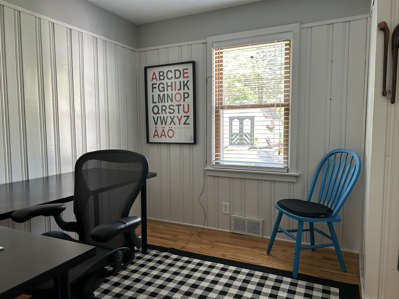 Office with board-and-batten walls, a black desk and a window to the yard