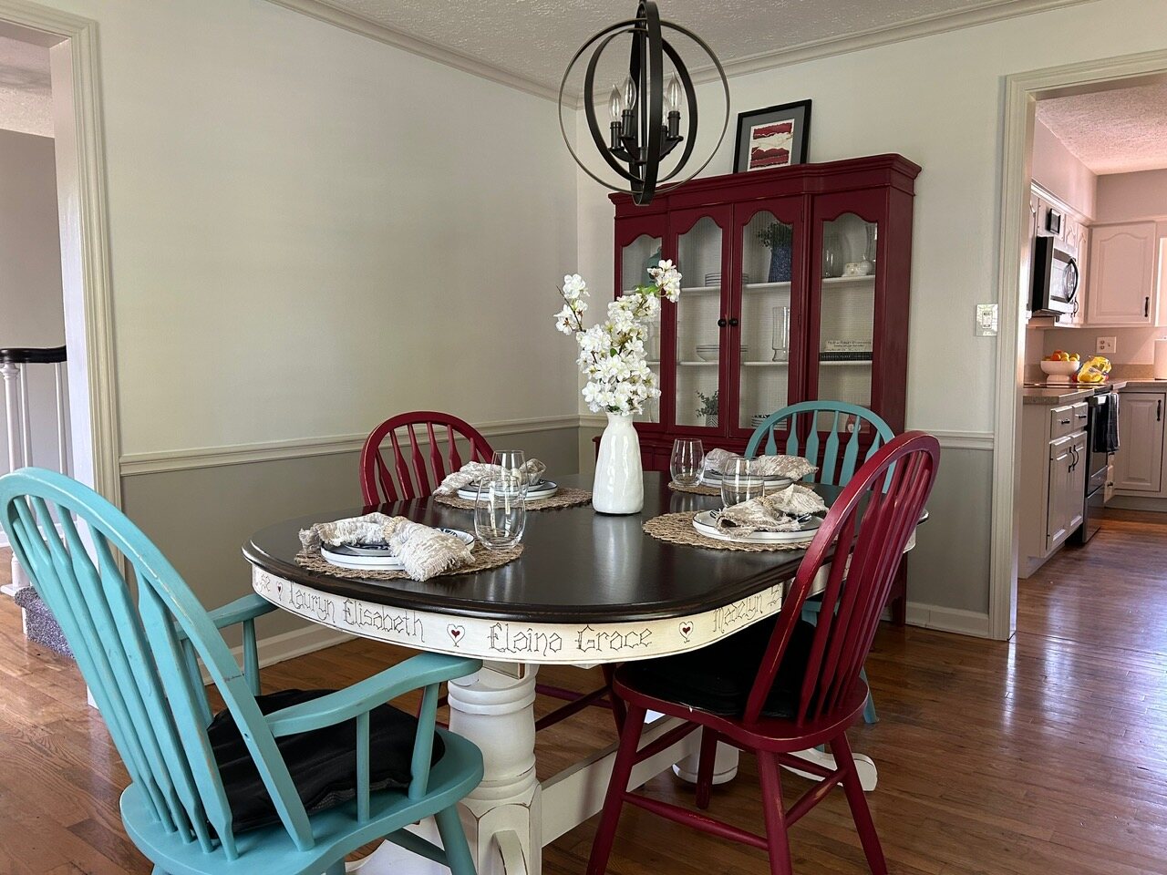 Dining room with a round table, a red hutch, and the kitchen beyond