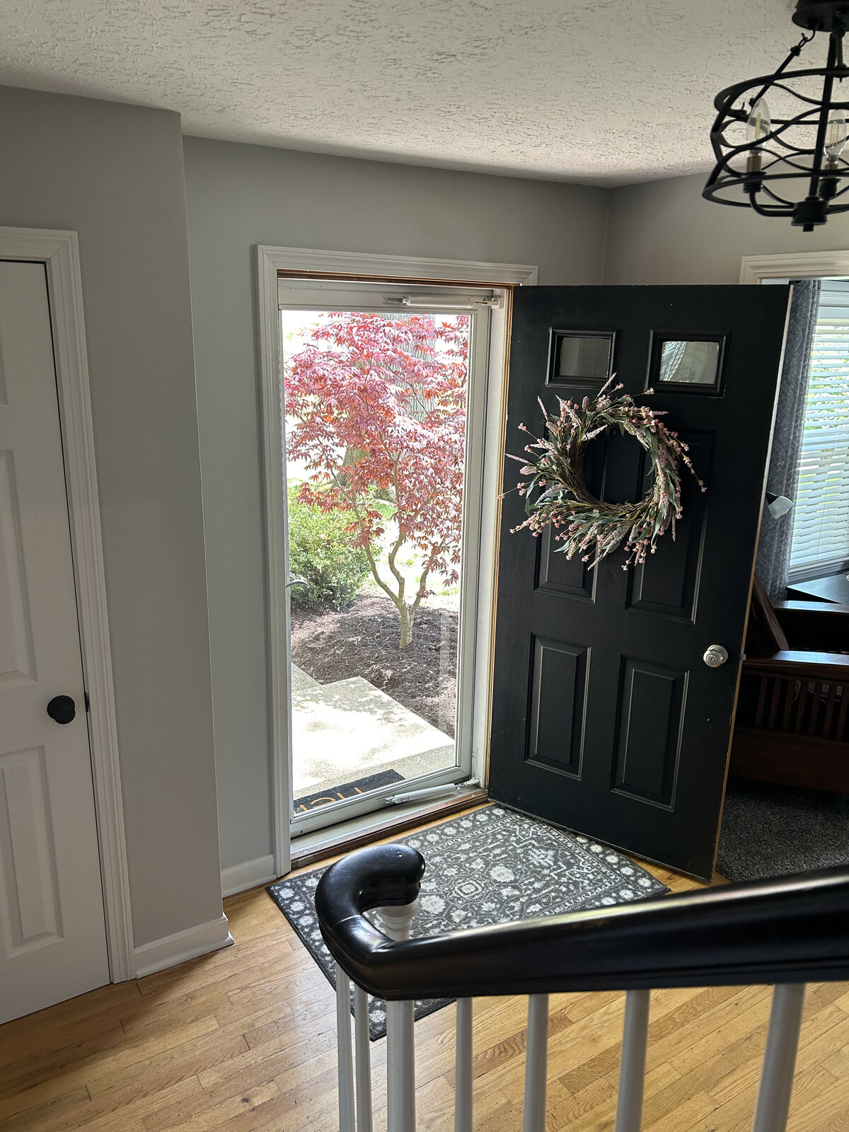 The black front door with a wreath, looking out to the yard