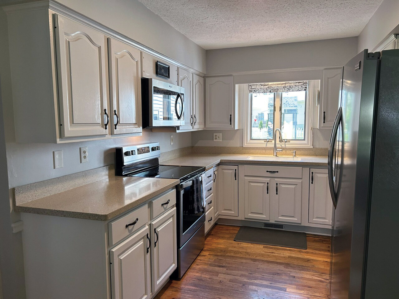 Kitchen with white cabinets, stainless range and microwave