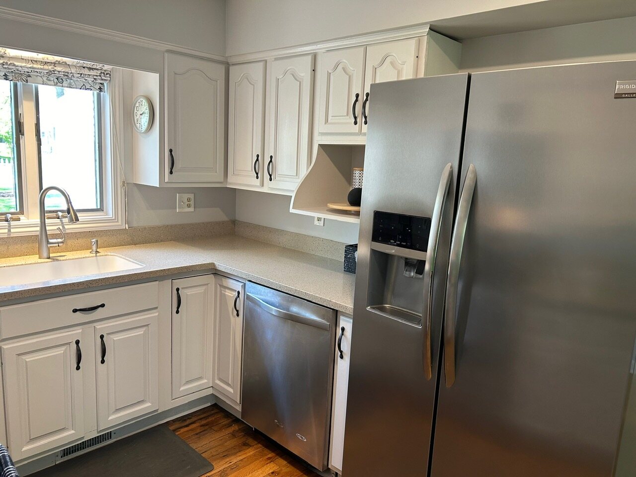 Kitchen sink under the window, dishwasher and stainless refrigerator
